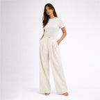 Woman wearing a white t-shirt and cream-colored wide-leg pants on a white background