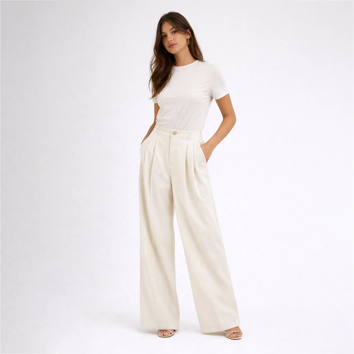 Woman wearing a white t-shirt and cream-colored wide-leg pants on a white background